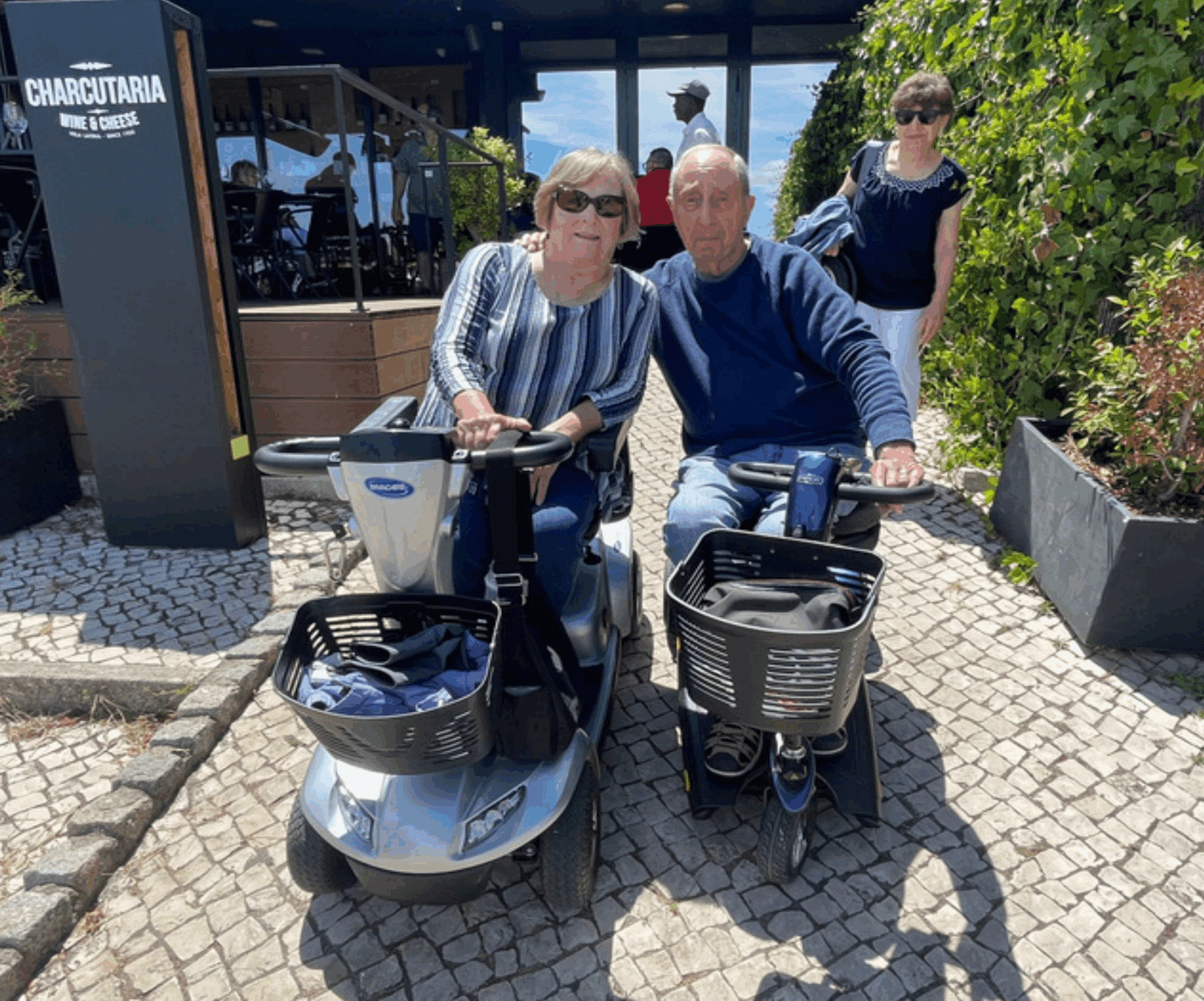 Elderly couple on mobility scooters outside cafe