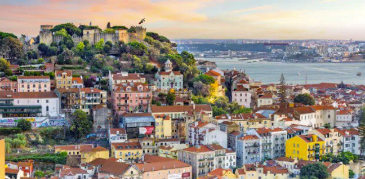 Colorful hillside buildings overlooking a calm waterfront at sunset.