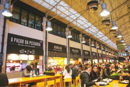 Busy indoor market with people dining and shopping.