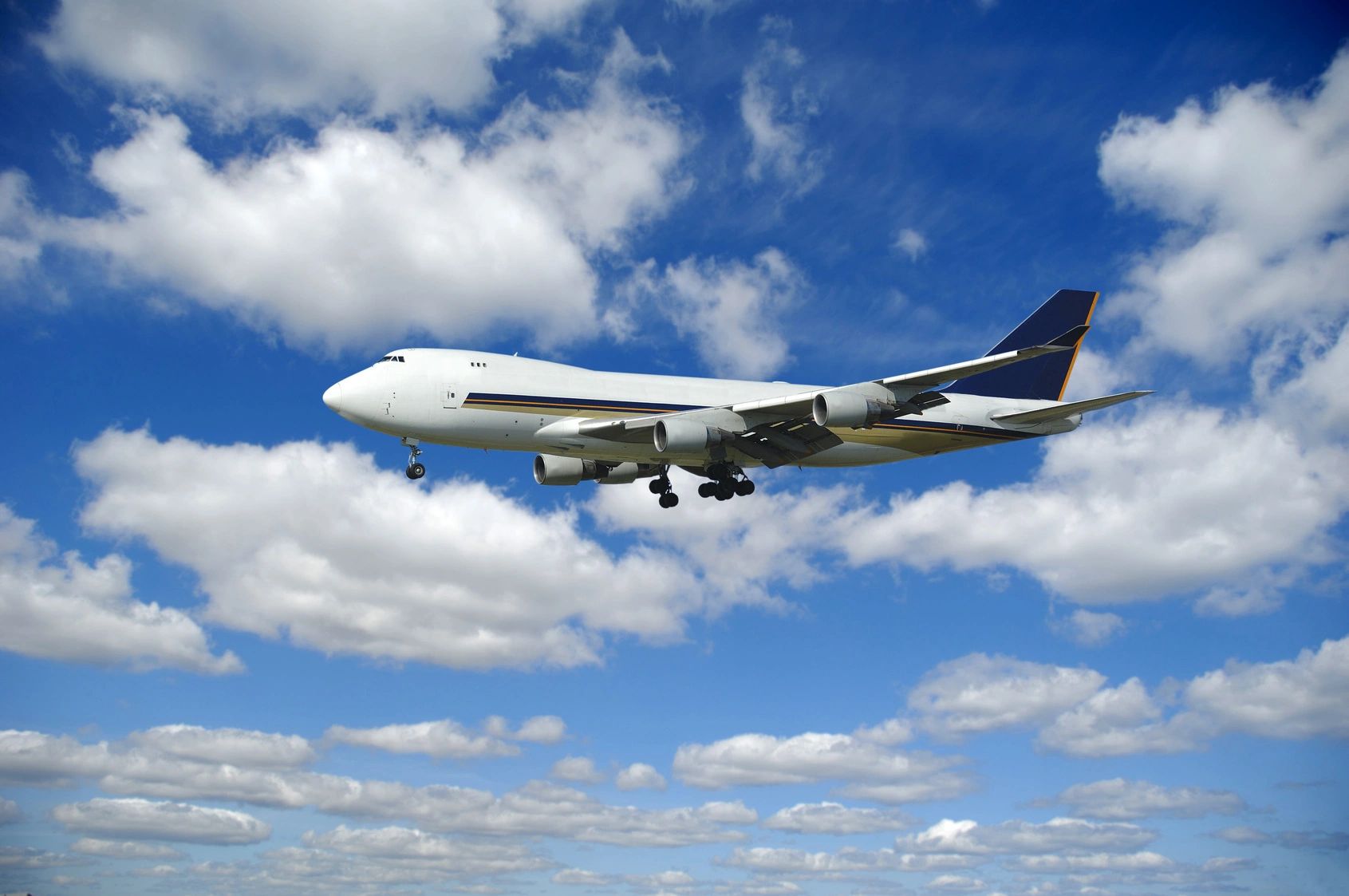 A large airplane flying in a partly cloudy blue sky.
