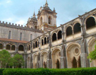 Historic cloister with arches and a bell tower under a blue sky.