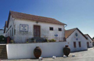 A rustic old white building with a tiled roof and wooden door.