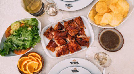 Grilled, glazed ribs served with chips and fresh lemon slices on a table.