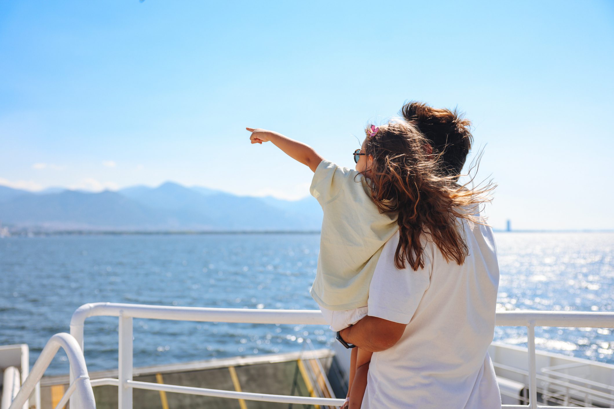 Mother and child pointing at the sea on a boat trip.