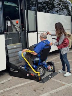 A person in a wheelchair is boarding a bus with assistance.