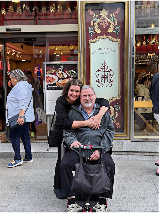 Two women happily hugging on a city sidewalk in front of a restaurant.